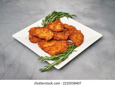 Organic Breaded Chicken Cutlet Served On A Plate With Rosemary Garnish