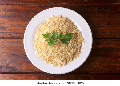 Organic Brown Rice Grain Cooked In White Dish On Rustic Wooden Table. Integral Rice Top View