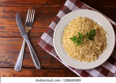 Organic Brown Rice Grain Cooked In White Dish On Rustic Wooden Table. Integral Rice Top View