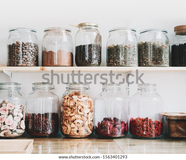 Organic bulk products in zero waste shop. Foods\
storage in kitchen at low waste lifestyle. Dried berries and fruits\
in glass jars on shelves. Eco friendly shopping in plastic free\
grocery store.