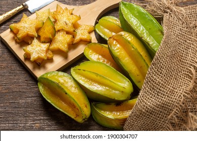 Organic carambola Asian fruit whole in a wicker basket and cut into a pine, carambola, grown on an organic farm on a rustic wooden table top, top view with space for writing - Shutterstock ID 1900304707