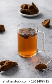 Organic Chaga tea in cup. Trendy Russian healthy infusion from birch mushroom on light background. Close up. Vertical