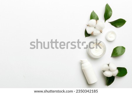 Organic cosmetic products with cotton flower and green leaves on white background. Copy space, flat lay.