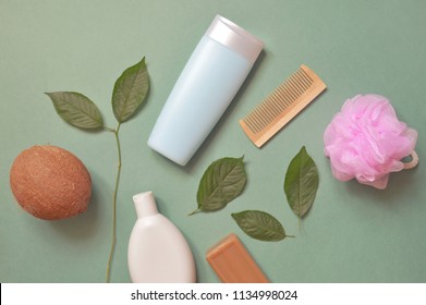 Organic cosmetics from natural ingredients. Coconut, shampoo, shower gel, pink sponge, tar soap, wooden comb and green leaves. Flat lay beauty photography bath products