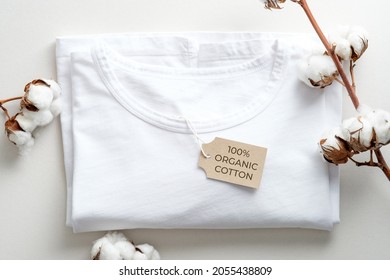Organic cotton t-shirt with cotton flowers on white background. Flat lay, top view. Eco clothing, sustainable lifestyle, fashion concept. - Shutterstock ID 2055438809
