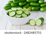 Organic cucumbers slices in a ceramic bowl on a light table, selective focus.