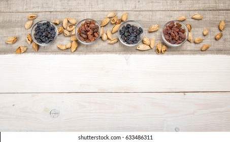 Organic dark and yellow raisins in glass bowls on wooden table background.