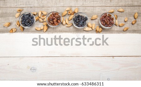 Organic dark and yellow raisins in glass bowls on wooden table background.