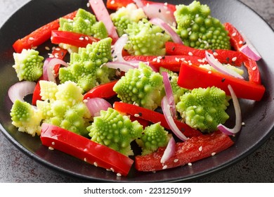 Organic diet fresh salad of romanesco broccoli, bell pepper and red onion sprinkled with sesame seeds close-up in a plate on the table. Horizontal
