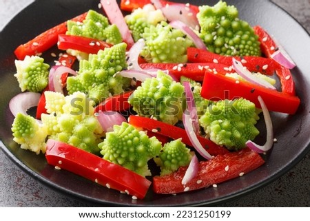 Organic diet fresh salad of romanesco broccoli, bell pepper and red onion sprinkled with sesame seeds close-up in a plate on the table. Horizontal