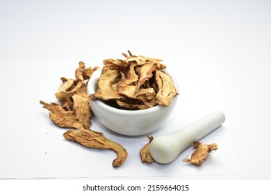 organic dried ginger in white ceramic mortar with pestle 