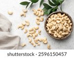 Organic dry cashew nuts in bowl, grey concrete table background. Top view