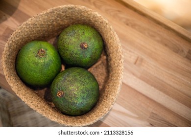 Organic farm avocado in straw basket on wooden table closeup. Fresh ripe green exotic fruits full of healthy nutriment vegetarian eating. Three tropical edible plant with twig for guacamole cooking - Shutterstock ID 2113328156