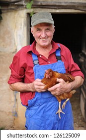 Organic Farmer Holding Chicken Under His Arms