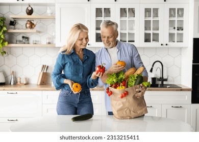 Organic Food Delivery. Happy Senior Couple Unpacking Bag With Groceries In Kitchen, Cheerful Elderly Spouses Holding Fresh Vegetables And Smiling, Mature Husband And Wife Enjoying Healthy Nutrition