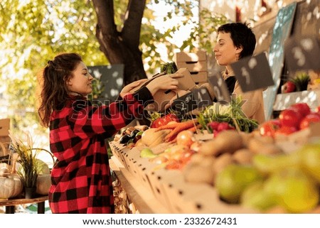 Organic food from farm. Young woman buying fresh herbs while shopping for local produce at farmers market. Female small business owner serving customer, selling home-grown fruits and vegetables