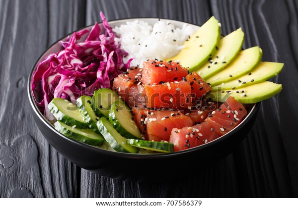 Organic food:\
tuna poke bowl with rice, fresh cucumbers, red cabbage and avocado\
close-up on the table.\
horizontal\
