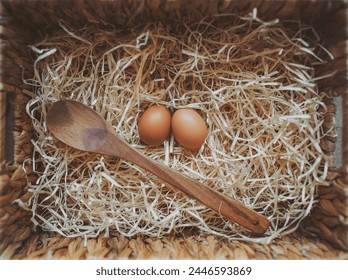 Organic fresh eggs and  wooden spoon in a straw nest. Easter eggs on wooden straw background in the early morning on Easter Holiday. Cooking concept. ready to cook. the concept of making dough.  - Powered by Shutterstock