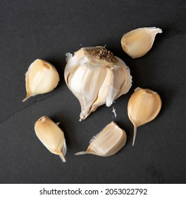 Organic Garlic Bulb And Cloves On A Dark Stone Countertop, Overhead View