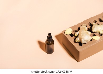 Organic Ginger Essential Oil In Dark Glass Bottle, Ginger Root And Brick Podium On Beige Background. Isometric View, Copy Space.