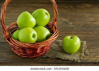 Organic Granny Smith Apples In A Wicker Basket On Wooden Table.