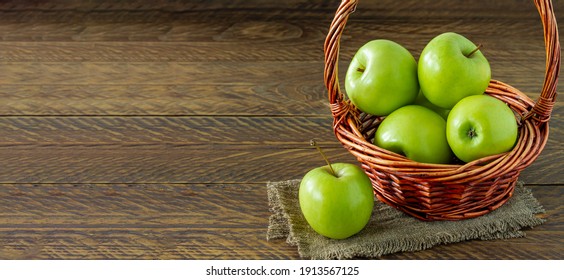 Organic Granny Smith Apples In A Wicker Basket On Wooden Table. Banner.