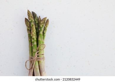 Organic green fresh asparagus tied with rope on white background. Copy space, top view, horizontal image.  Asparagus officinalis. Spring healthy cooking idea concept