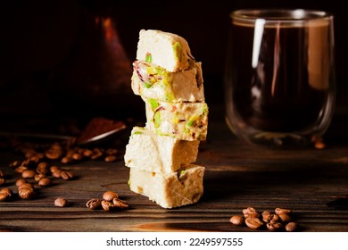 Organic halva with pistachios on a wooden surface. Traditional oriental sweets. Fresh coffee, copper cezve and scattered coffee beans on background. Jewish, Turkish, Arabic oriental national dessert - Shutterstock ID 2249597555