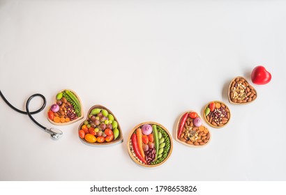 Organic  healthy  food ,grains  in  wooden  bowls,stethoscope  and  red  heart  shape  on  white  background  for  the  health  concept