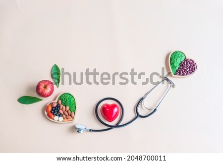 Organic  healthy  food  in  wooden  bowls , red  heart  shape ,medical  stethoscope  and  an  apple  on  pastel  background  for  the  health  concept