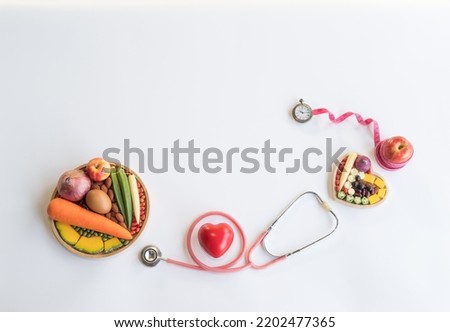 Organic healthy  food  in  wooden  bowls , medical  stethoscope , red  heart shape  and  tape  measure  wrapped  around  the  apple  on  white  background for  the  health  concept .
Top  view .