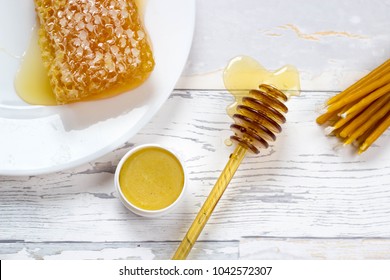 organic honeycomb, honey lip balm and natural wax candles on wooden white background