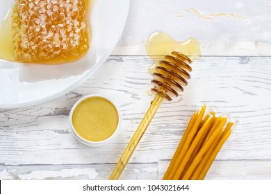 organic honeycomb, honey lip balm and natural wax candles on wooden white bakcground