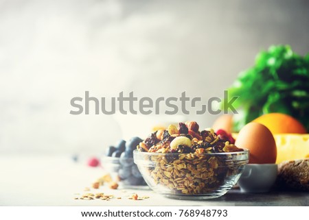 Organic ingredients for healthy lunch - berries, milk, egg, oatmeal on grey concrete background. Copy space. Healthy breakfast concept.