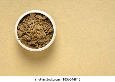 organic noni fruit powder from Hawaiian evergreen shrub in a small ceramic bowl against handmade paper, top view with a copy space, nutritional supplement