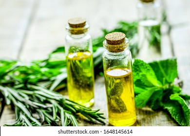 Organic Oil In Bottle With Rosemary And Mint On Light Table Background