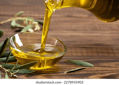 Organic olive oil pouring from carafe  into glass bowl - Powered by Shutterstock