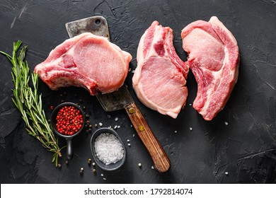 Organic Pork meat chop set over american classic butcher knife or cleaver with spices and rosemary and red pepper on black slate table top view. - Shutterstock ID 1792814074