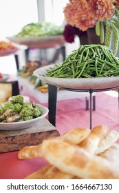 Organic Prepared Salads, Vegetables And Fruit On Dishes, Laid Out For A Party. A Laden Table. Flowers In A Vase. A Farmstand Food Stall.