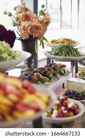 Organic Prepared Salads, Vegetables And Fruit On Dishes, Laid Out For A Party. A Laden Table. Flowers In A Vase. A Farmstand Food Stall.