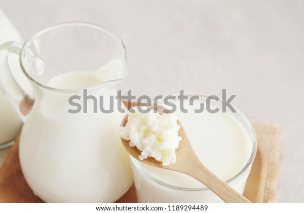 Organic probiotic milk kefir grains, Tibetan mushrooms on wooden spoon and kefir milk in glass containers, gut health