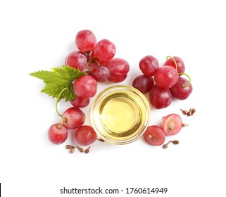 Organic red grapes, seeds and bowl of natural essential oil on white background, flat lay