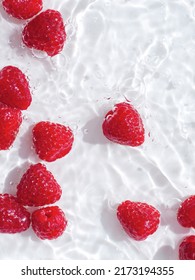 Organic Ripe Raspberries In Splashing Water On The White Background. Top View