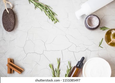 Organic skincare products flatlay with oil bottle, pumice, olive oil, tonic lotion , clay face mask and body butter on clean minimalist grey concrete background with copy space