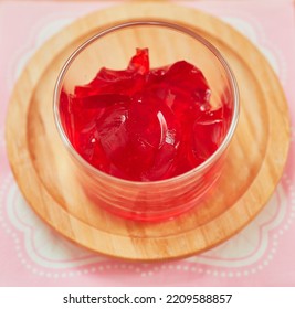 Organic Strawberry Gelatin Snack Is Served In A Small Glass Cup And Set On A Bamboo Plate Over A Pink Napkin