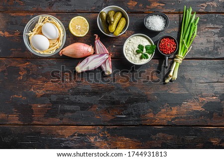 Organic tartar ingredients in a row pickles, capers, dill, parsley, garlic, lemon over old wood table and space for text concept on bottom