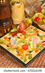 Organic Veal Scallops, Serving Spoon Spilling Out Yellow, Red Cherry Tomatoes, Celery On Square Artisan, Plate, And A Clear Glass Bowl Of Tomatoes, An Olive Oil Pitcher And A Wood Pepper Grinder