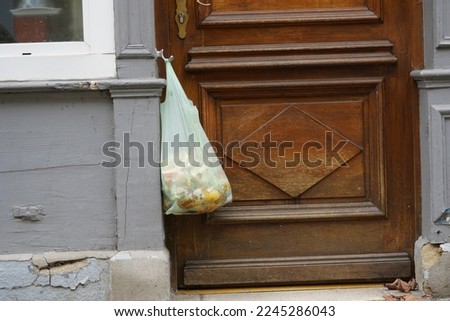 Organic waste in a plastic bag hanging on a door knob of a house front door. A cutout of a facade of a residential building in Altkirch, Frankreich. There is copy space available. Stock photo © 