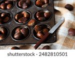 Organically harvested chestnuts being Prepped ready for roasting and eating. Sitting in a tray on a black background with a autumn aesthetic.