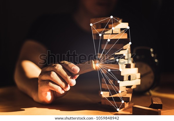 organization ideas concept with\
hand pull out block of wooden piece from stack strategy and risk\
concept